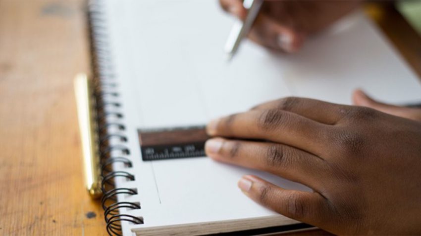 Hands writing in notebook